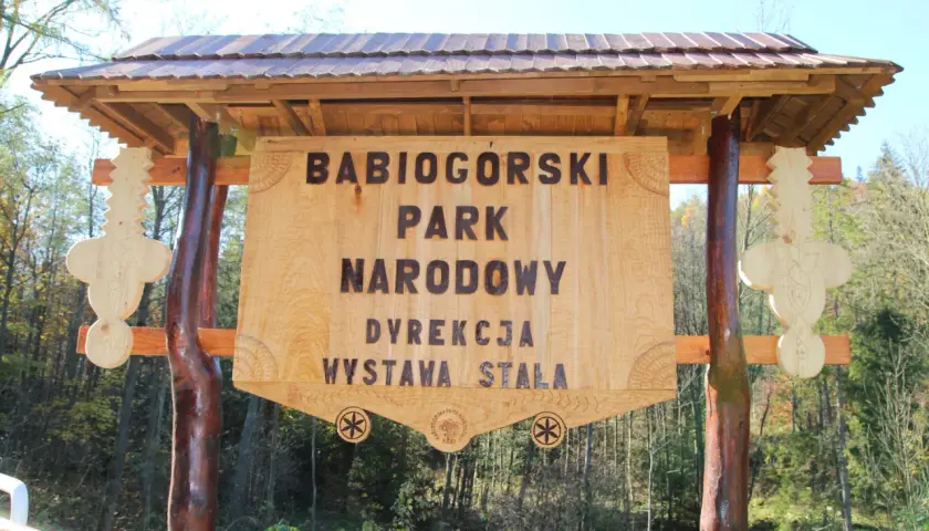 Drewniana tablica informacyjna Babiogórskiego Parku Narodowego. Zapowiada zawoja atrakcje i wystawę stałą.