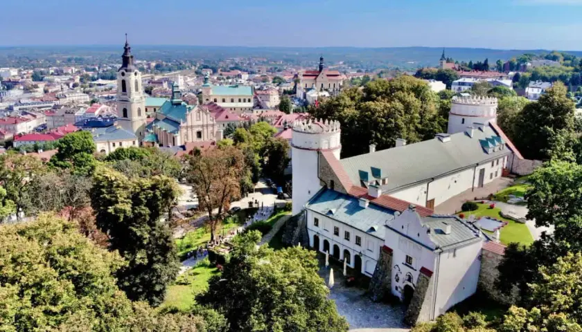 Zamek w Sandomierzu i miasto z wieżą kościelną. Warto przemyśl atrakcje tego miejsca, spacerując po zielonych terenach.