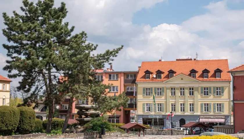 Rynek w Sobótce z kamienną rzeźbą i kolorowymi kamienicami. Idealne miejsce na spacer i odkrywanie lokalnych atrakcji.