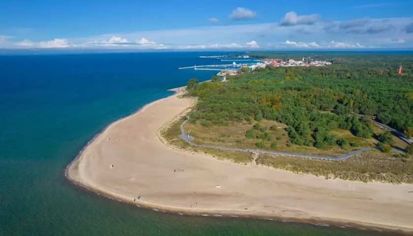 Piękna plaża i las na Helu. W oddali widać miasteczko i port. Idealne miejsce na wakacyjne atrakcje.