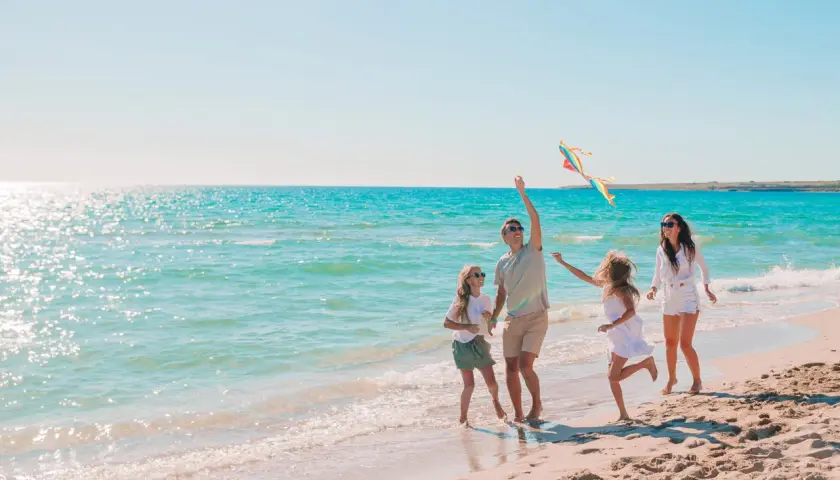 Rodzina z dziećmi puszcza latawiec na plaży. Idealne miejsce, gdzie nad morze z niemowlakiem, by cieszyć się słońcem i falą.