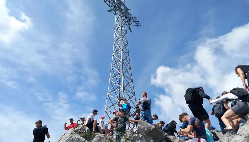 Tłum turystów na skalistym szczycie pod krzyżem, gdzie jest Giewont.