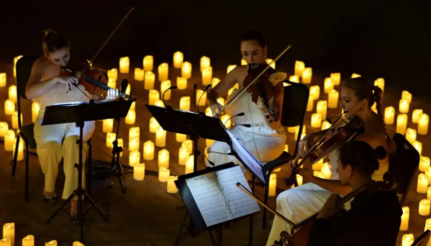 Nastrojowy koncert przy świecach w Poznaniu. Kobiety grają na skrzypcach w otoczeniu setek płonących świec.