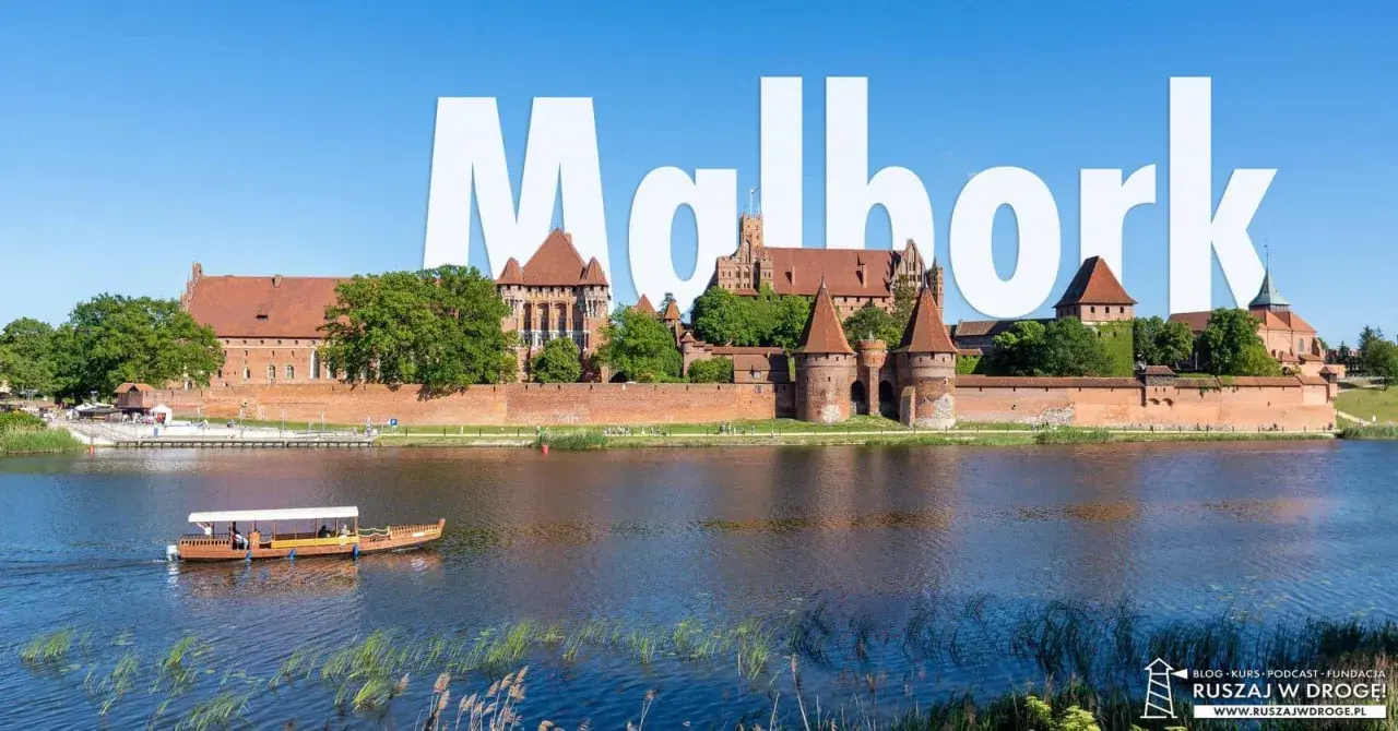 Malbork atrakcje: potężny zamek krzyżacki nad rzeką, z łodzią turystyczną na pierwszym planie.