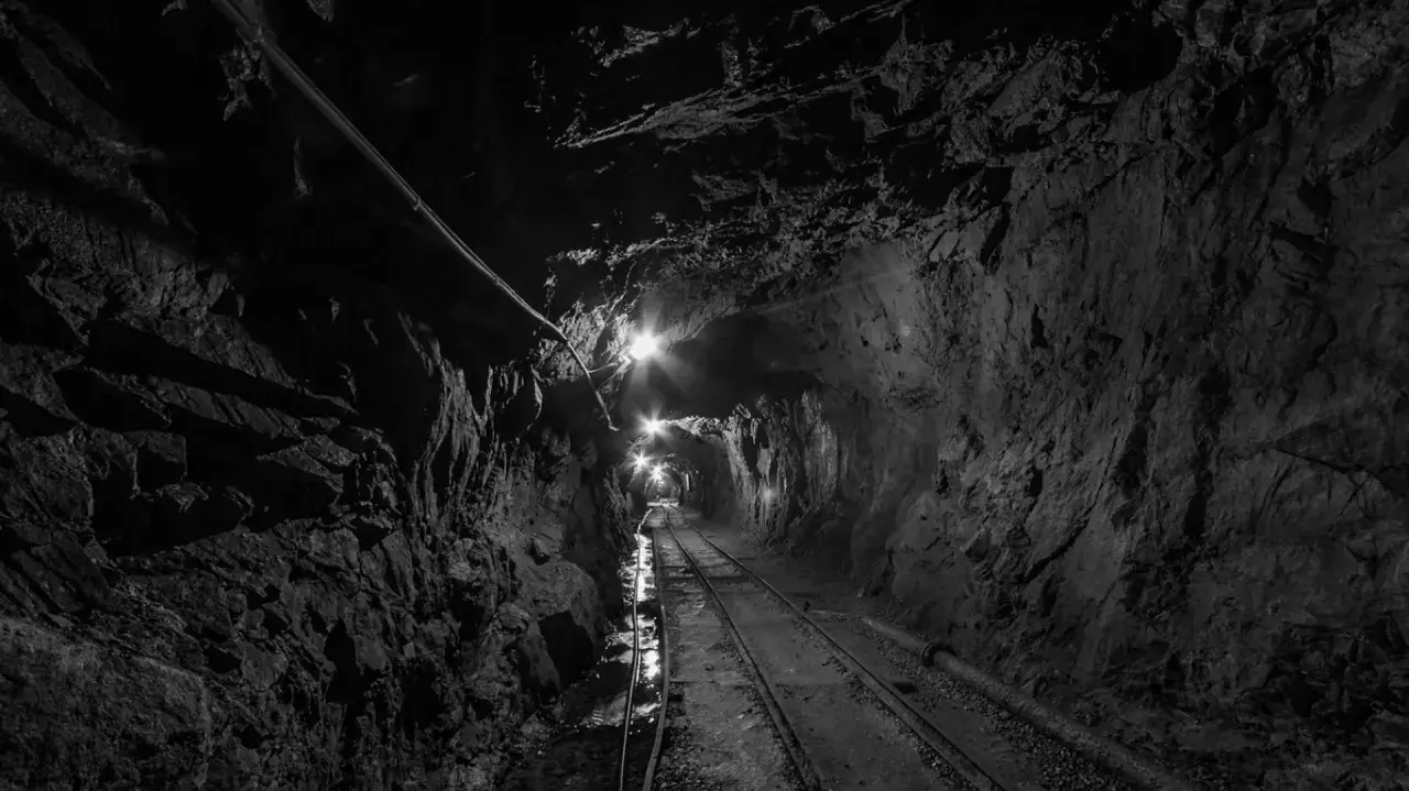 Wydobycie w kopalni złoty stok. Tunel kopalniany z torami i oświetleniem, prowadzący w głąb ziemi.
