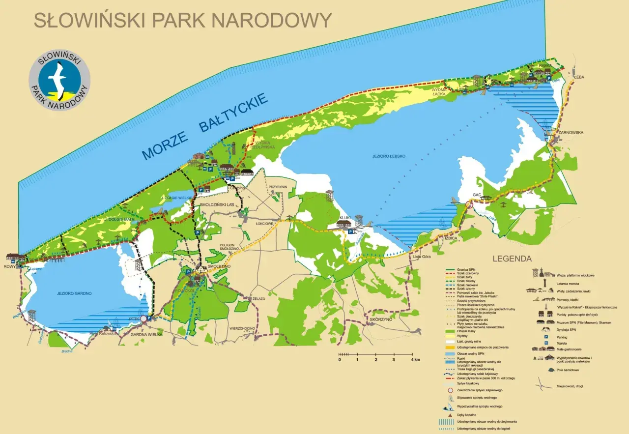 Mapa turystyczna Słowińskiego Parku Narodowego z zaznaczonymi szlakami, jeziorami, wydmami i miejscowościami.