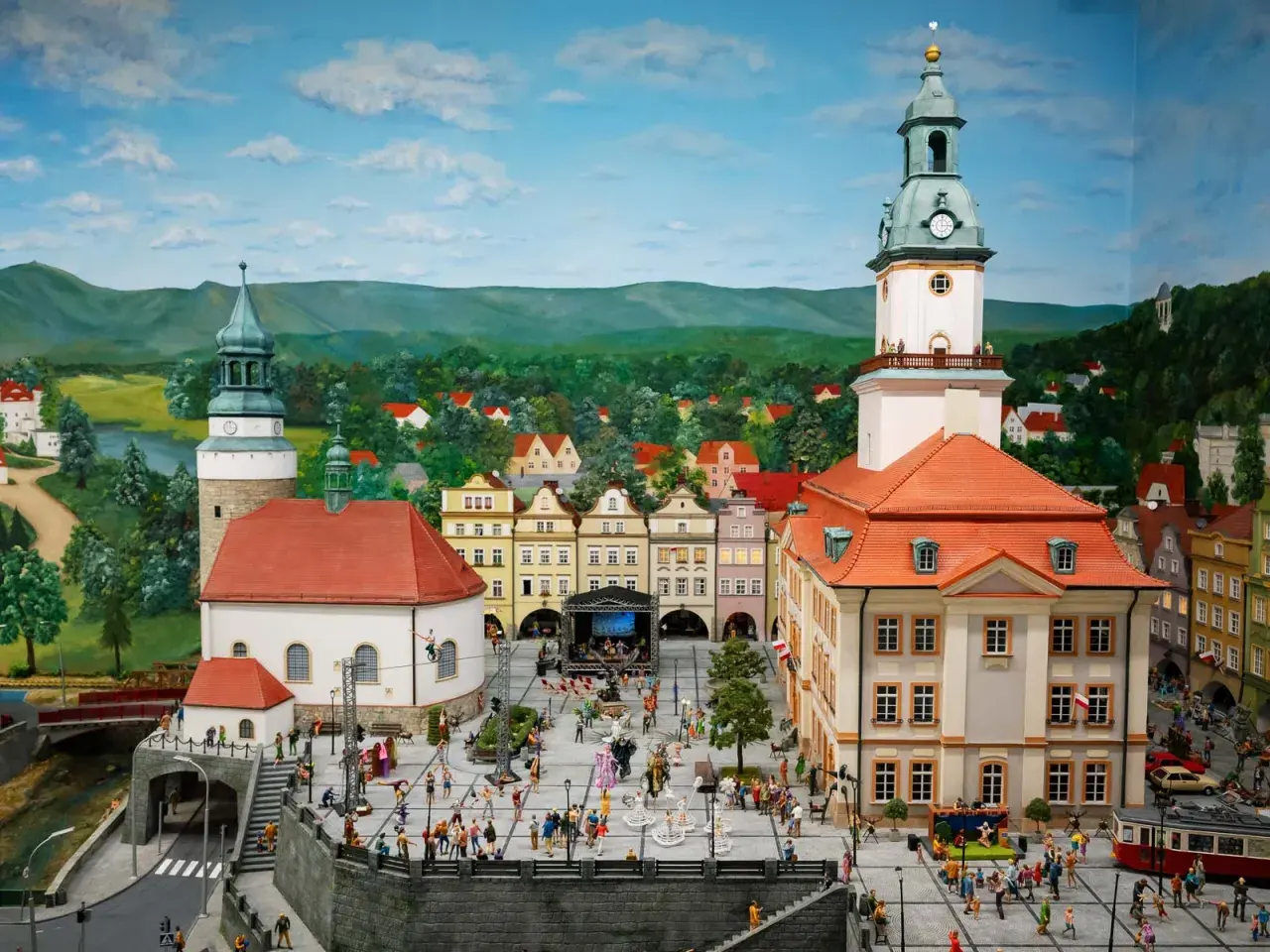 Miniaturowy rynek w Jeleniej Górze, z wieżą ratuszową, kamieniczkami i tłumem ludzi.