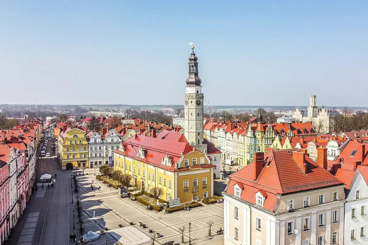Rynek w Bolesławcu z ratuszem i wieżą zegarową. Kolorowe kamienice i brukowany plac tworzą urokliwe bolesławiec atrakcje.
