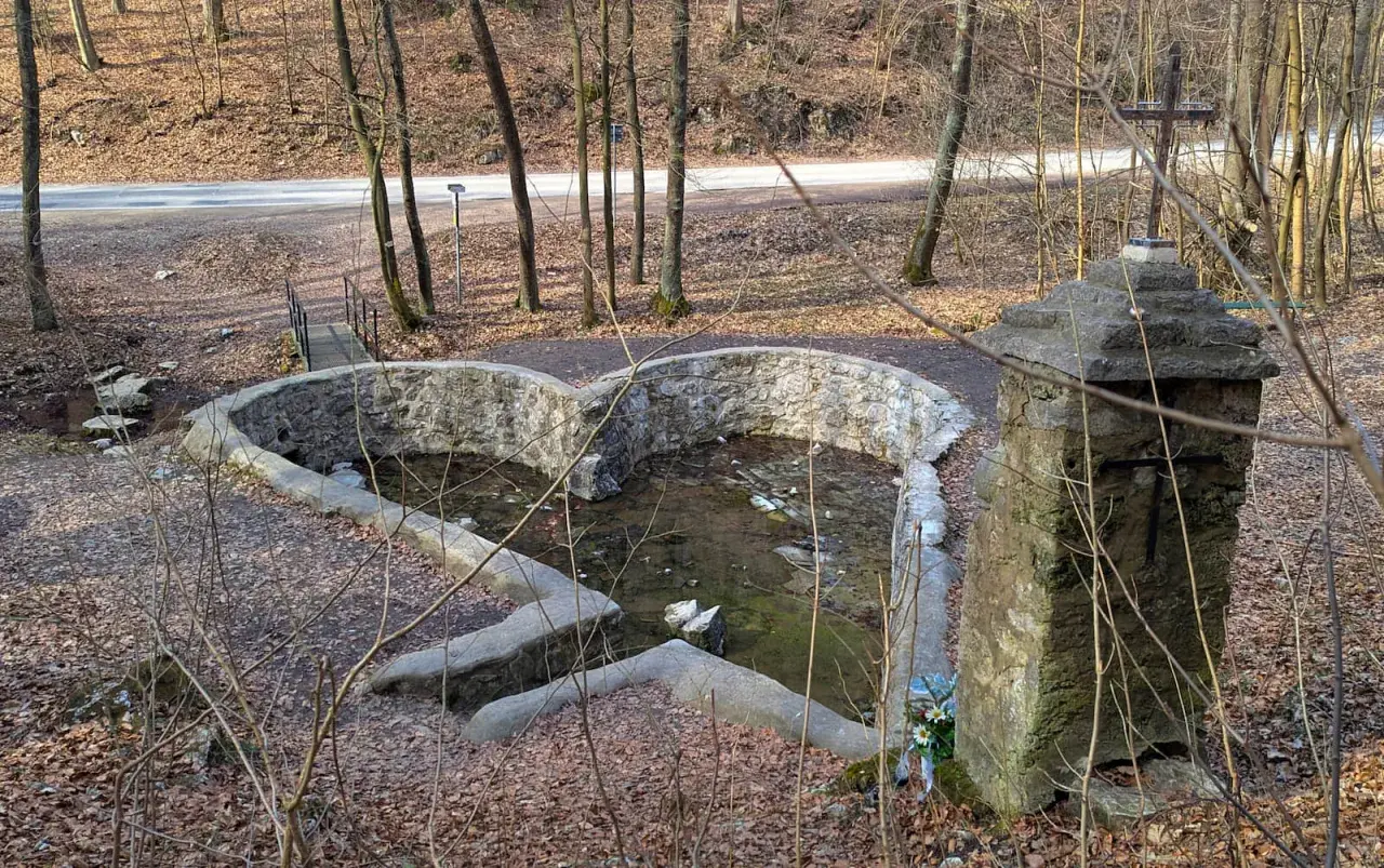 Kamienny krzyż i sercowate źródełko w dolinie Eliasówki, otoczone jesiennym lasem.