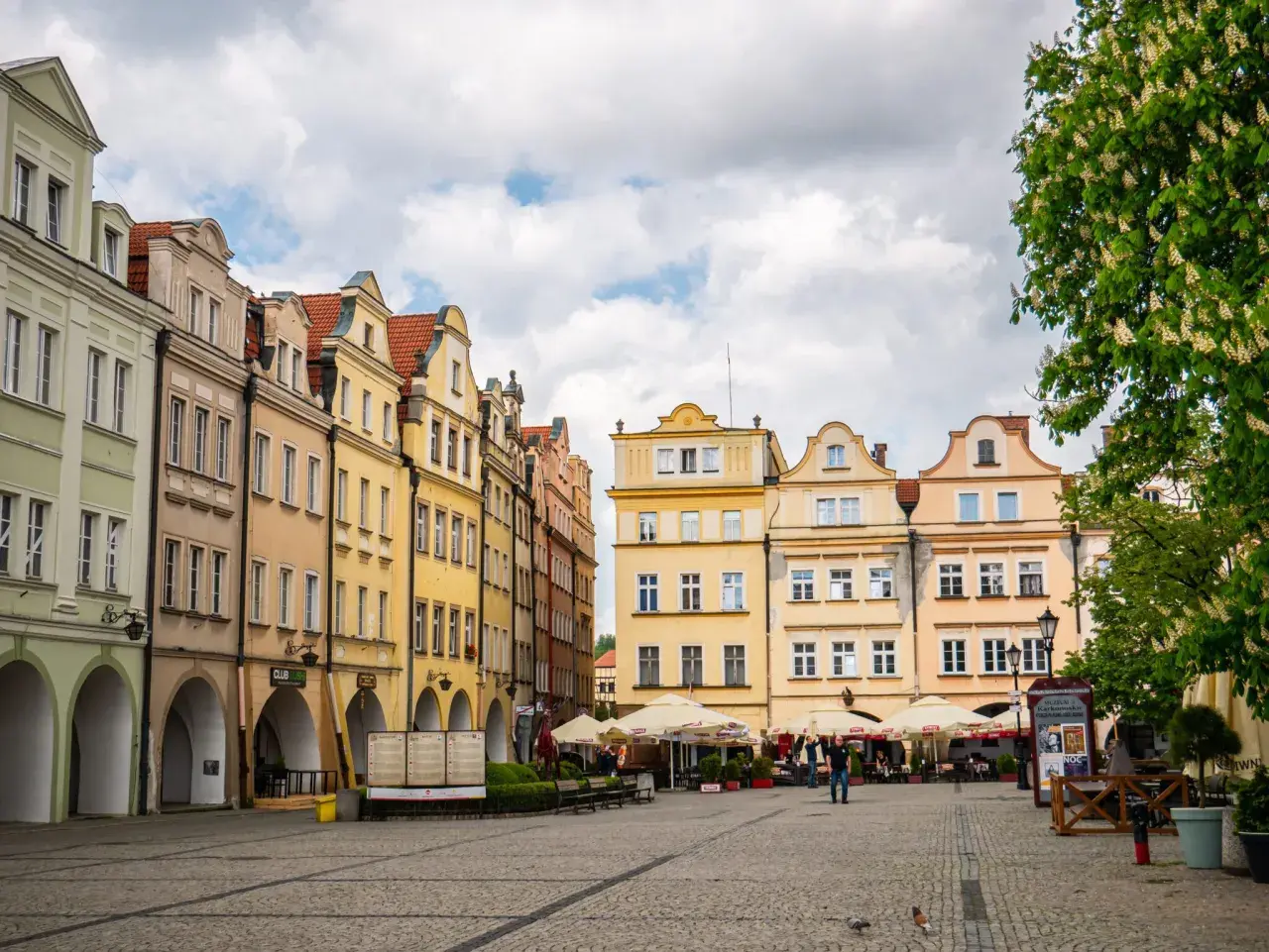 Kolorowe kamienice na rynku w Jeleniej Górze, z arkadami i ogródkami kawiarnianymi. Atrakcje miasta czekają!