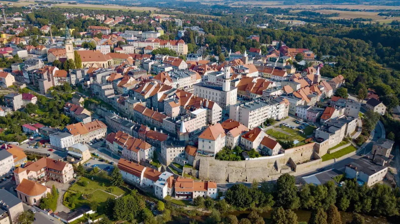 Widok z lotu ptaka na urokliwe miasto Bystrzyca Kłodzka z charakterystycznymi czerwonymi dachami i zabytkową architekturą.
