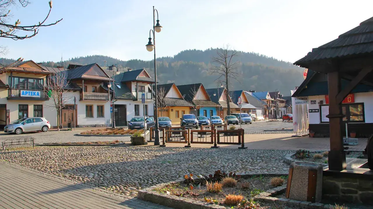 Urokliwy rynek z brukowaną nawierzchnią, kolorowe domki i góry w tle tworzą atmosferę małej Grecji.