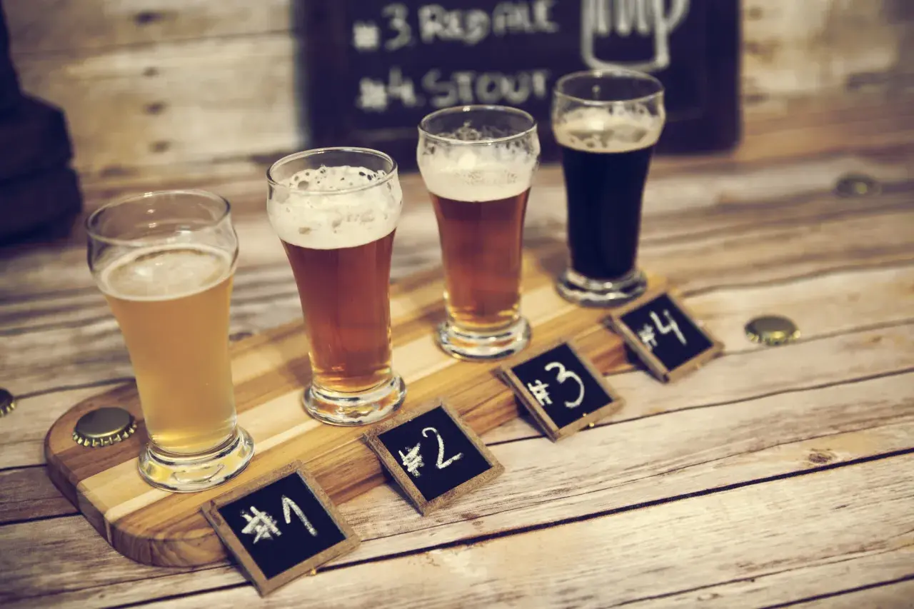 Degustacja piwa w Poznaniu: cztery szklanki z różnymi piwami, oznaczone numerami od 1 do 4, na drewnianej desce.