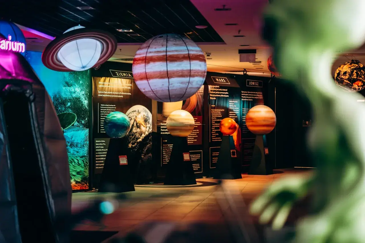 Interaktywne muzeum w Warszawie prezentuje modele planet. Widać Jowisza, Marsa i Ziemię, a także Saturna z pierścieniami.