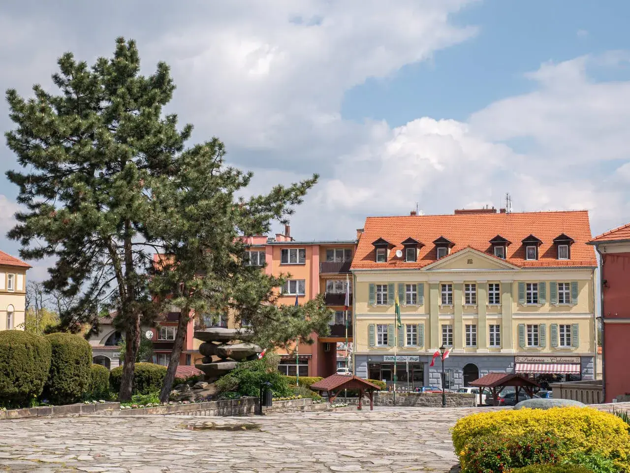 Rynek w Sobótce z kamienną rzeźbą i kolorowymi kamienicami. Idealne miejsce na spacer i odkrywanie lokalnych atrakcji.