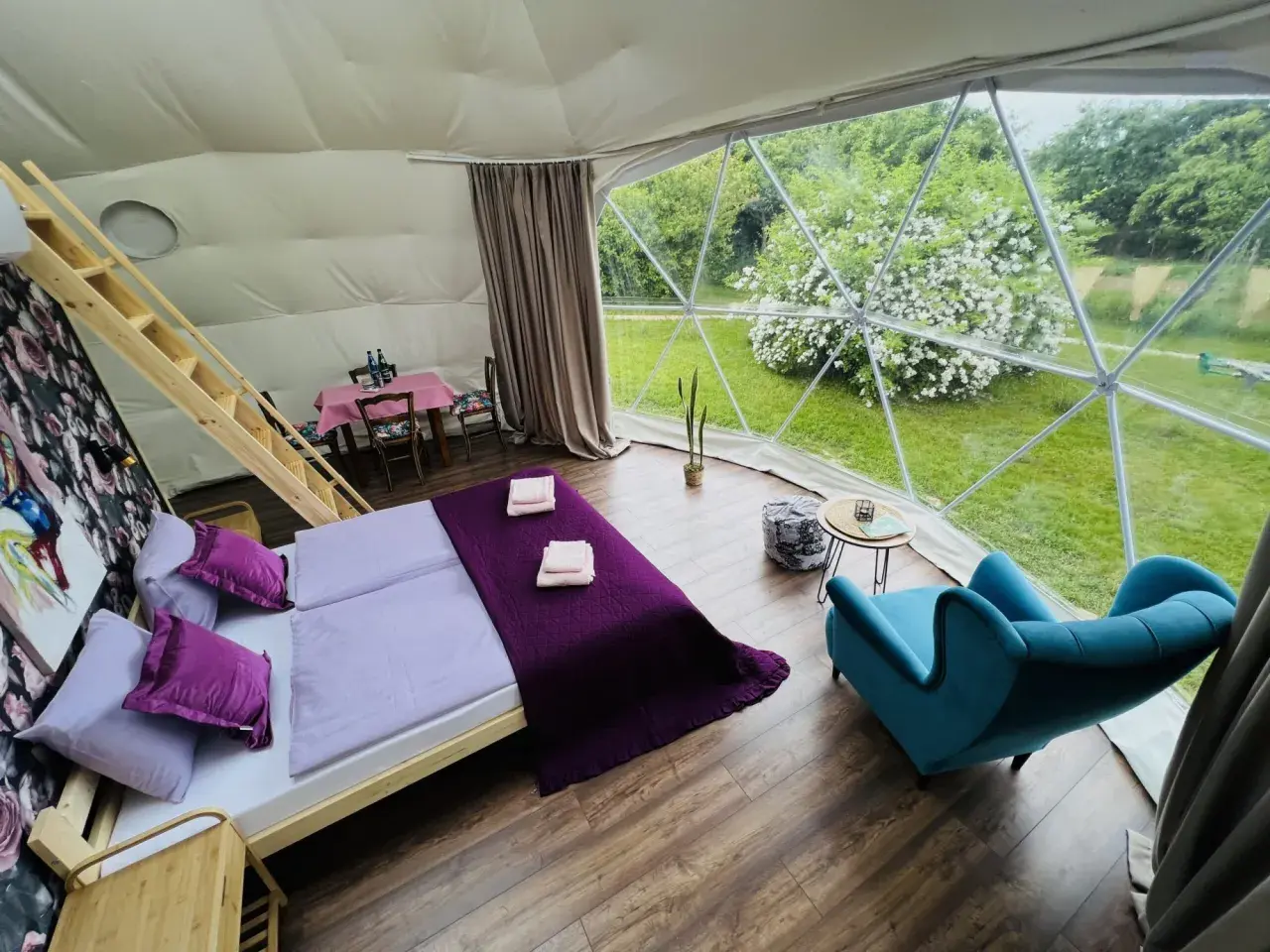 Przytulne wnętrze namiotu sferycznego z wygodnym łóżkiem i widokiem na zieleń. Idealne miejsce na glamping w Nałęczowie.