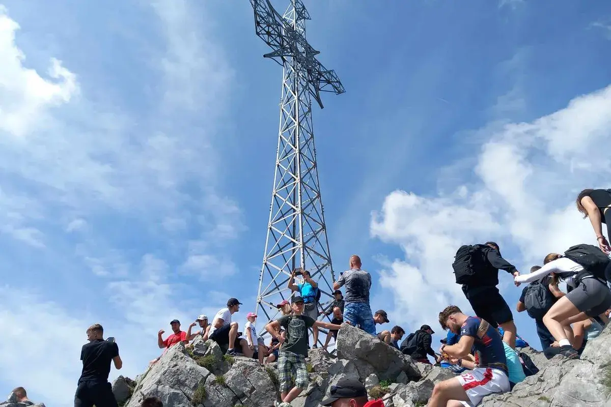 Tłum turystów na skalistym szczycie pod krzyżem, gdzie jest Giewont.