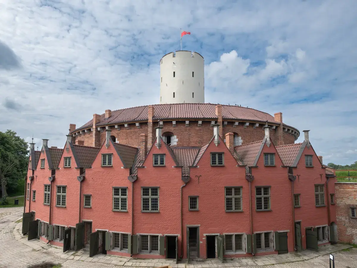 Gdańsk atrakcje dla dorosłych: Twierdza Wisłoujście z charakterystyczną wieżą i ceglanymi budynkami. Idealne miejsce na spacer i odkrywanie historii.