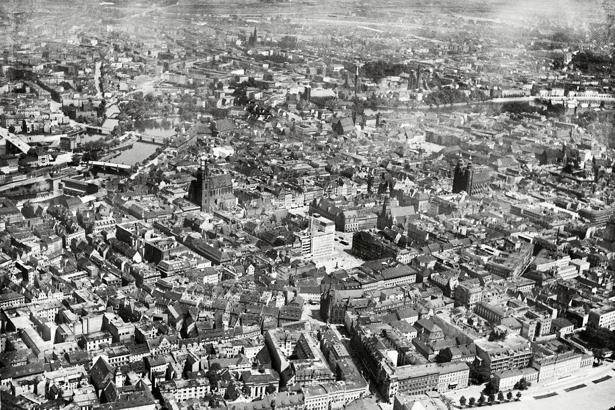 Widok z lotu ptaka na stare miasto Wrocław. Widać liczne kamienice, kościoły i rzekę.
