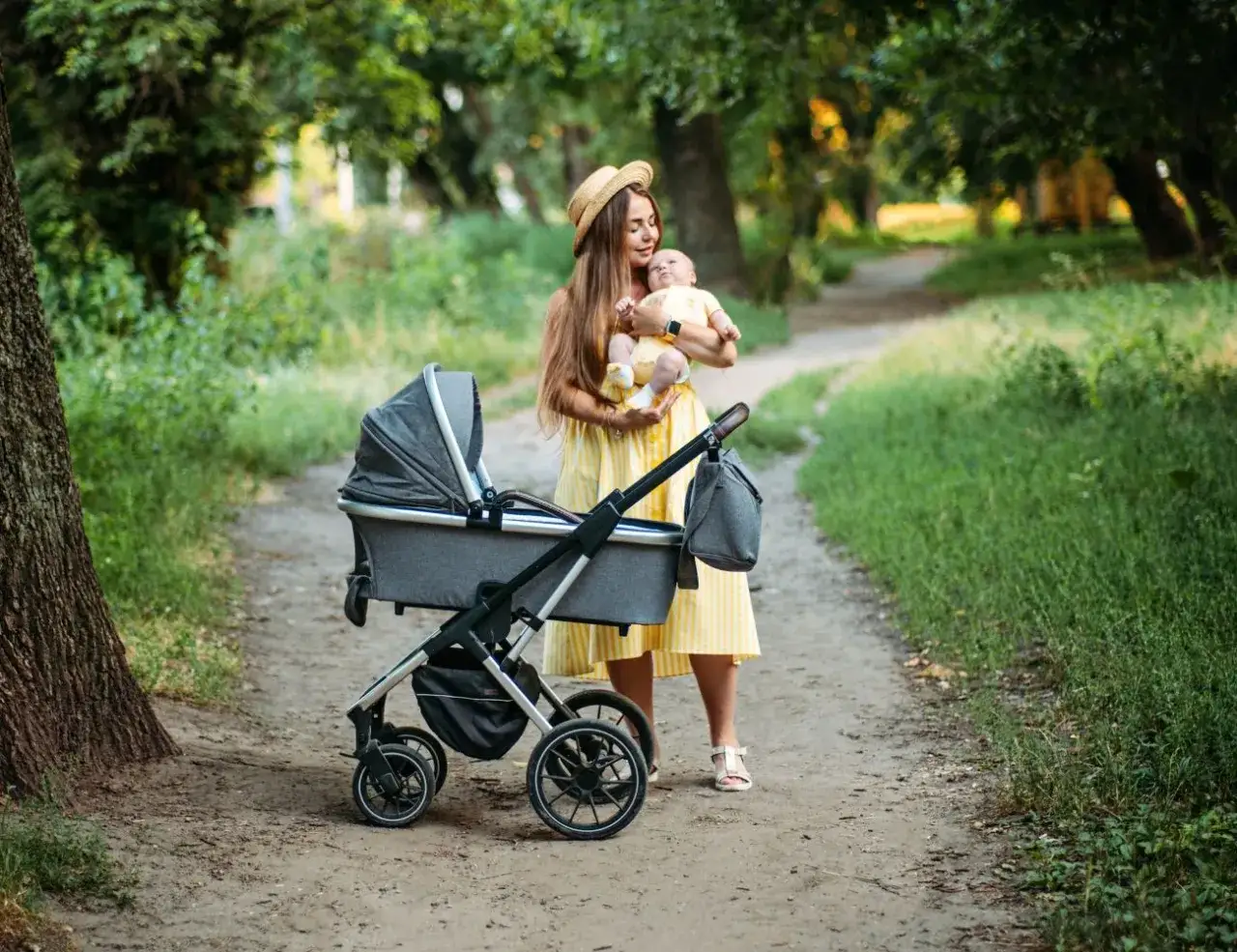 Mama z niemowlakiem w wózku, planuje gdzie nad morze z niemowlakiem. Słoneczny dzień w parku.