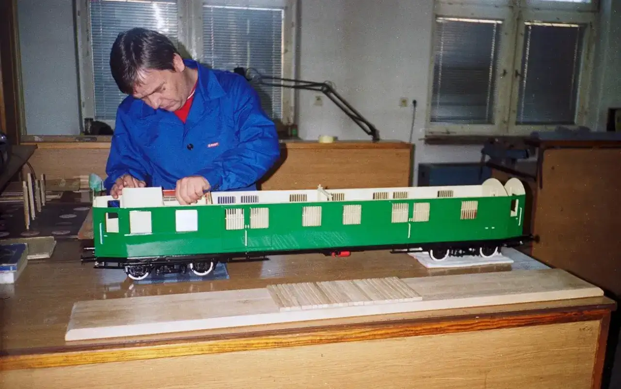 Majster składa zielony wagon kolejkowy w Jeleniej G&oacute;rze.