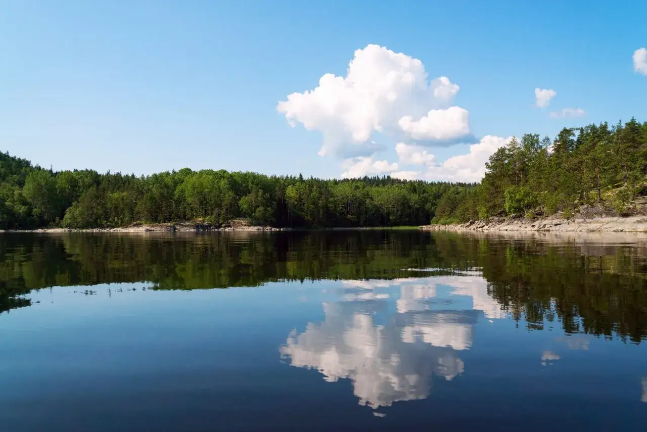 Spokojna tafla jeziora odbija zielone lasy i puszyste chmury. Idealne mazury atrakcje dla miłośników natury.