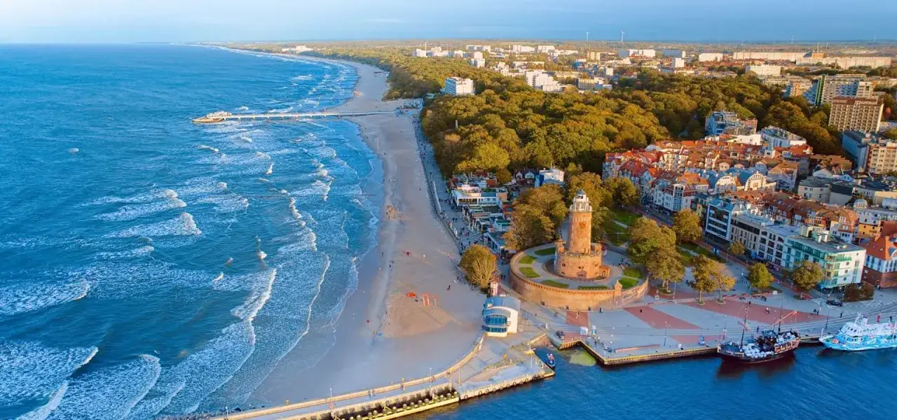 Widok na plażę, molo i latarnię morską w Kołobrzegu. To jedne z głównych kołobrzeg atrakcje, które przyciągają turystów.