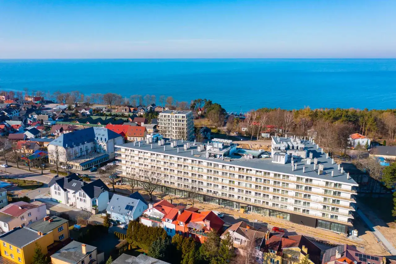 Jarosławiec atrakcje: nowoczesny apartamentowiec i kolorowe domki nad Bałtykiem.