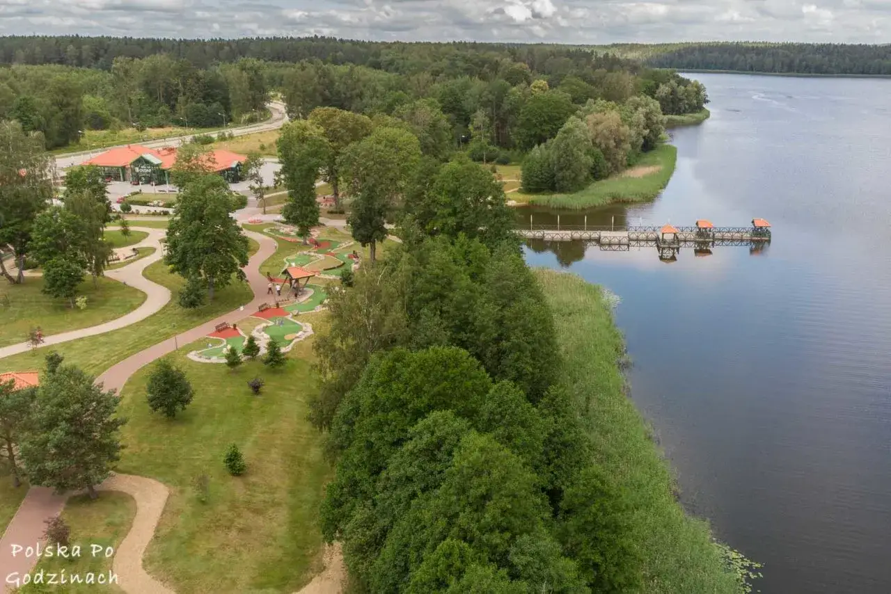 Malownicze gołdap atrakcje: pole do minigolfa, promenada nad jeziorem, pomost z altanami i las.