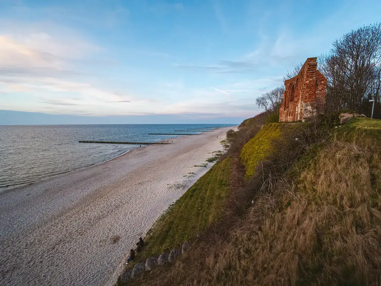 Ruiny kościoła na klifie nad Bałtykiem, plaża i falochrony. Trzęsacz atrakcje przyciągają miłośników historii i pięknych krajobrazów.