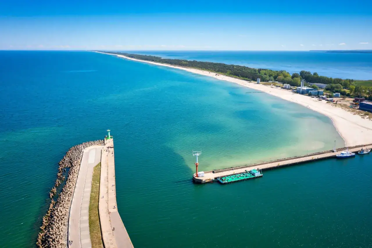 Władysławowo i okolice: malownicza plaża, molo z latarnią morską i statkami, oraz spokojne morze.