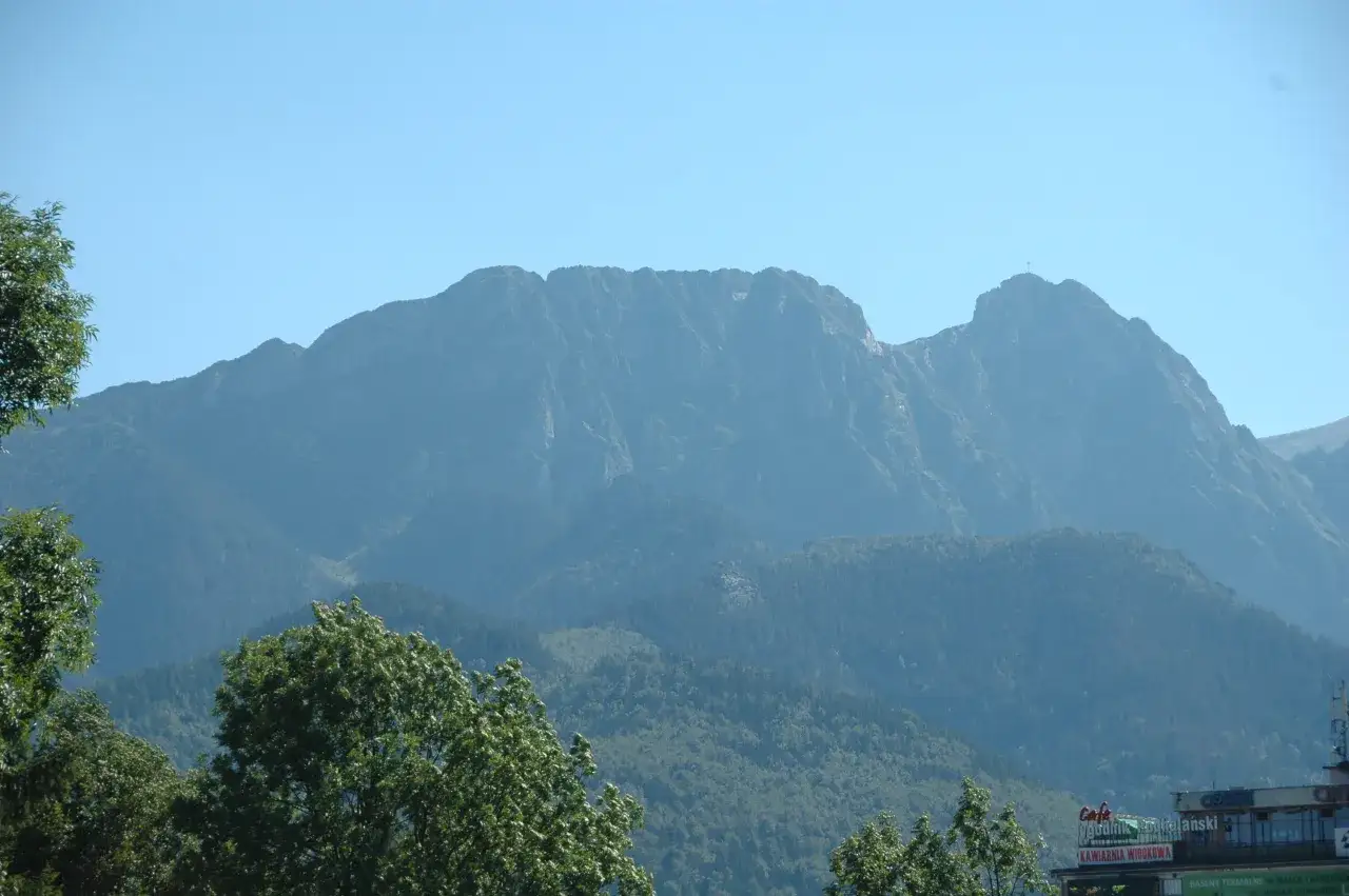 Giewont, majestatyczny szczyt Tatr, góruje nad lasami. Gdzie jest Giewont? Właśnie tam, na horyzoncie.