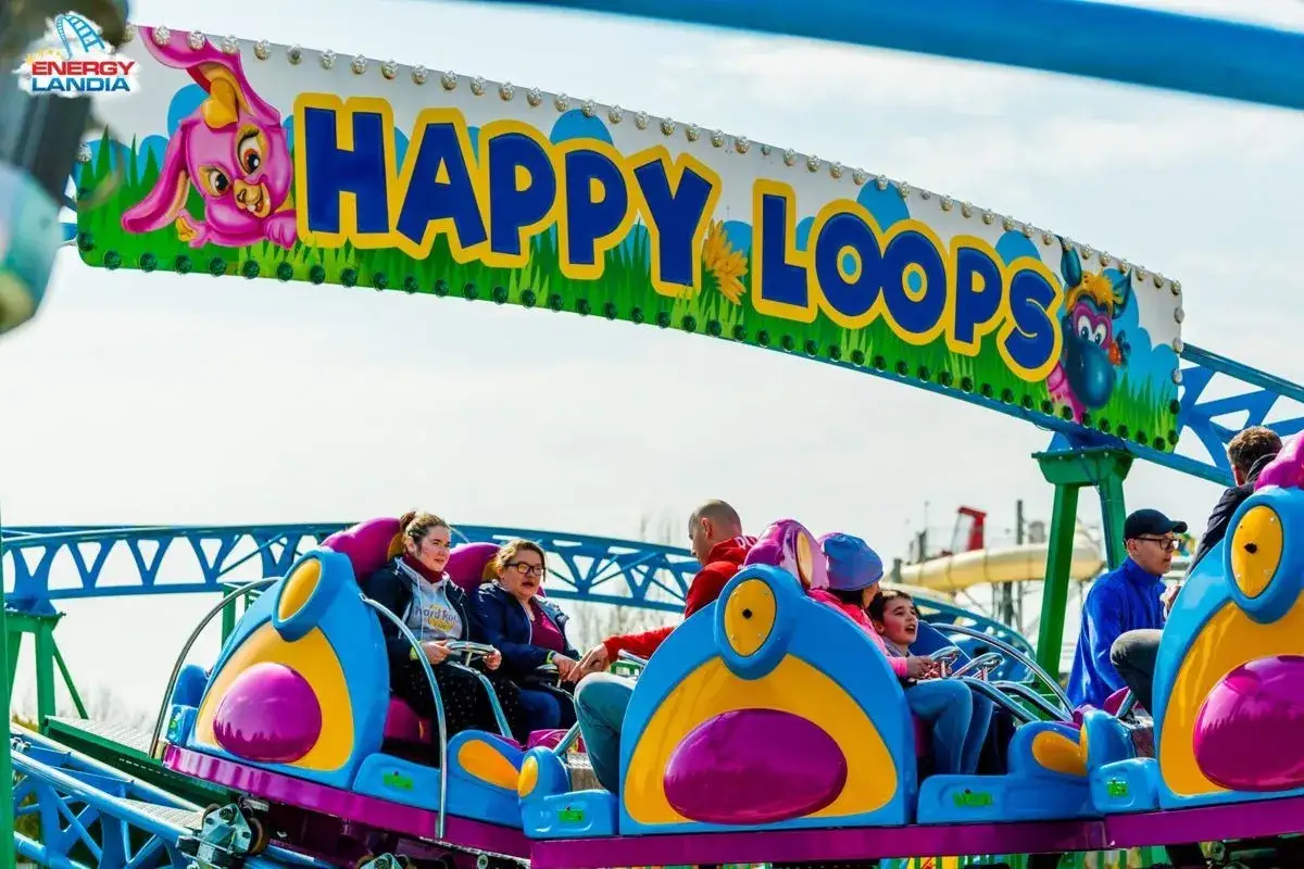 Radość na karuzeli Happy Loops w parku rozrywki Małopolska. Uśmiechnięci pasażerowie cieszą się przejażdżką.