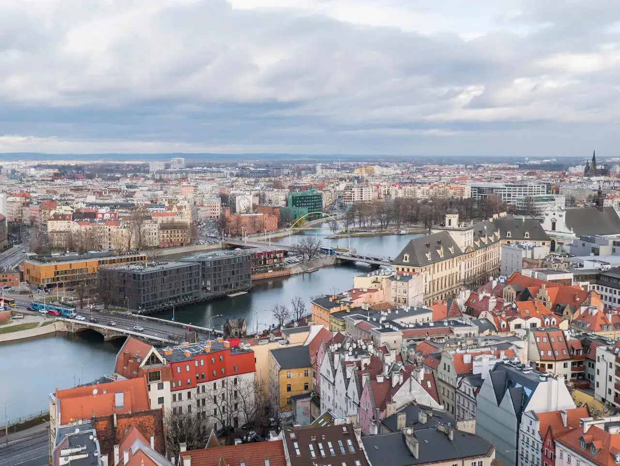 Widok na Wrocław z wież widokowych Dolny Śląsk. Rzeka, mosty i zabytkowa zabudowa miasta pod pochmurnym niebem.