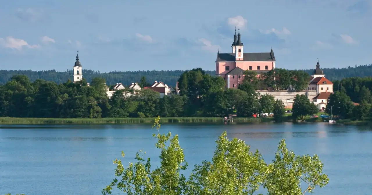 Malownicze suwałki atrakcje: klasztor kamedułów nad jeziorem, otoczony zielenią.