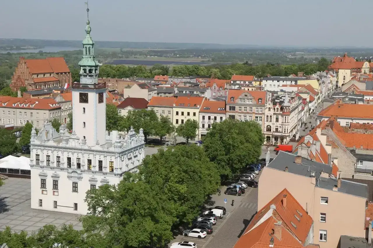 Widok na rynek w Chełmnie z ratuszem i wieżą. W tle kamienice i zieleń. To jedne z wielu chełmno atrakcje.
