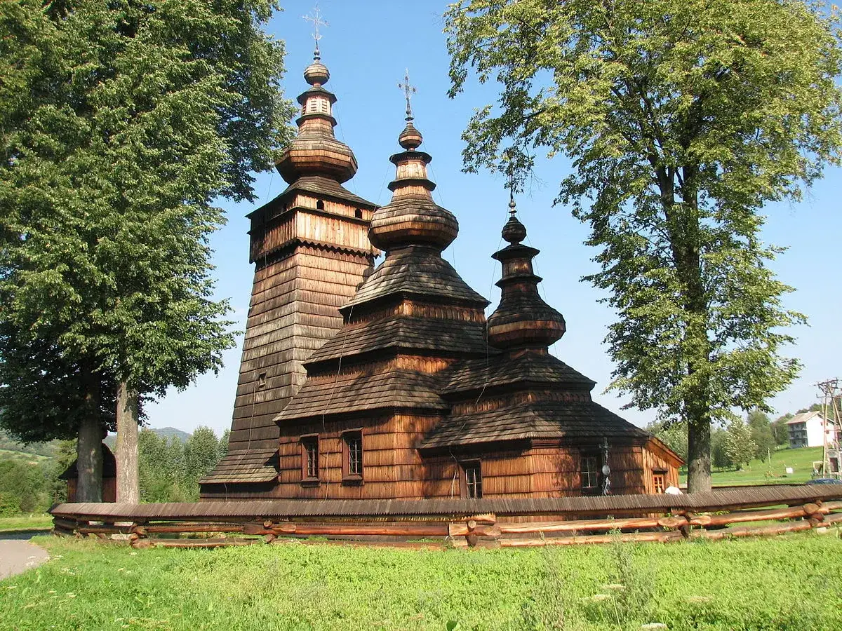 Drewniana cerkiew, jeden z pięknych zabytk&oacute;w w Polsce, z charakterystycznymi kopułami i wieżą, otoczona zielenią.