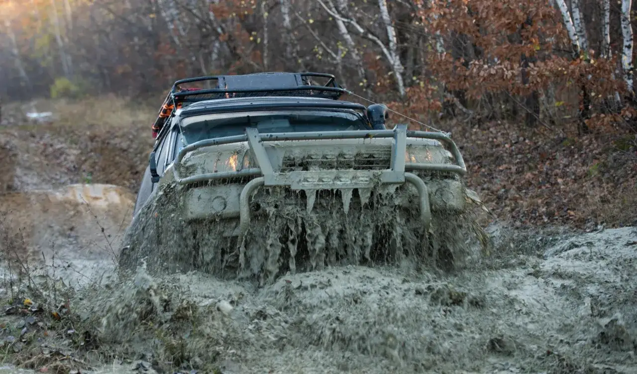 Samoch&oacute;d terenowy walczy z błotem podczas off road w Warszawie. Błoto bryzga spod k&oacute;ł, tworząc widowiskowy spektakl.