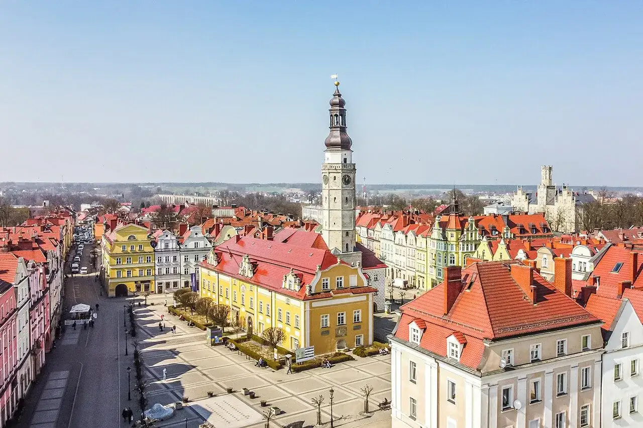 Rynek w Bolesławcu z ratuszem i wieżą zegarową. Kolorowe kamienice i brukowany plac tworzą urokliwe bolesławiec atrakcje.