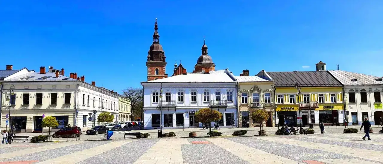 Rynek w Nowym Sączu z zabytkowymi kamienicami i wieżami kościelnymi. Idealne miejsce na spacer i odkrywanie atrakcji Nowego Sącza.